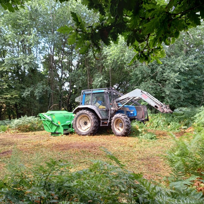 A tractor with a green flail collector on back of tractor
