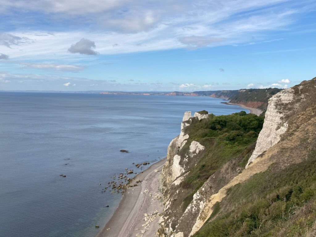 A cliffside view of rocks falls next to sea