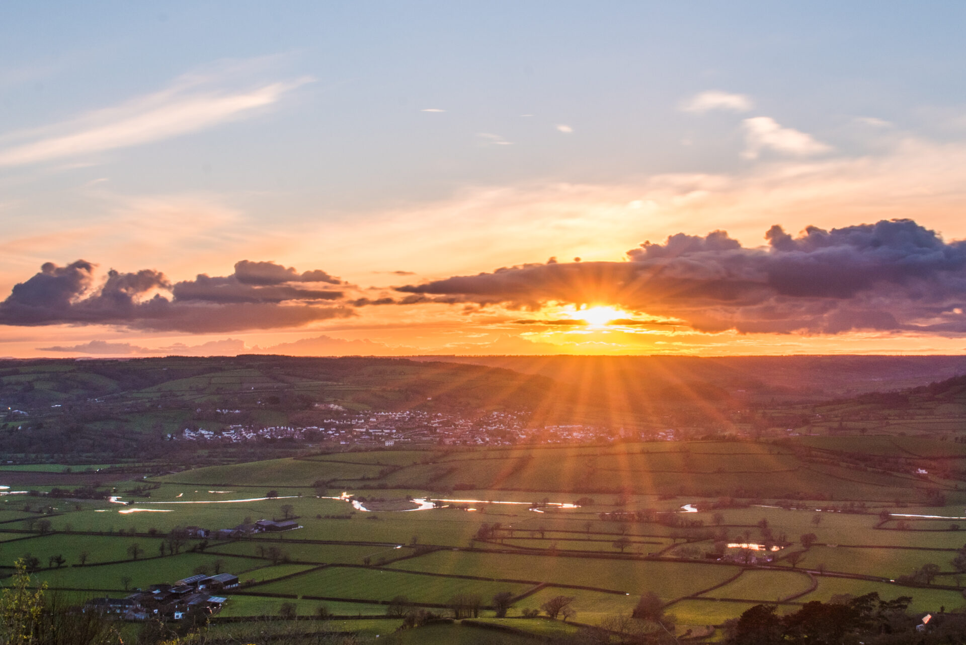 sunrise over green fields and hedgerows in a far reaching view