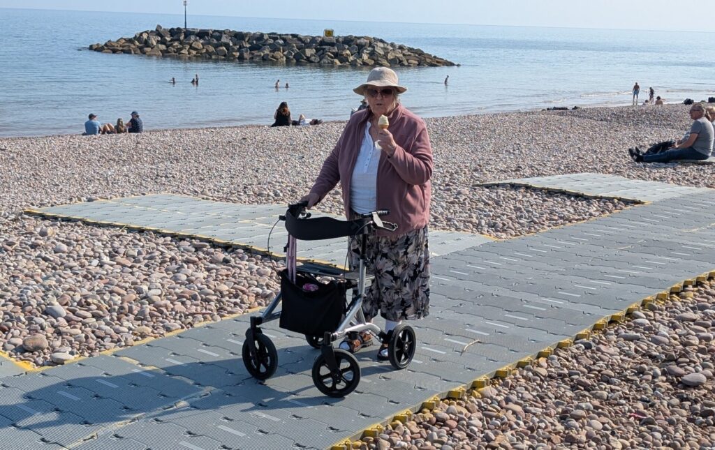 A lady eating icecream on plastic matting on the beach