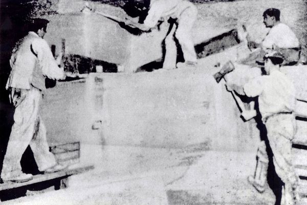 old black and white photo of men cutting large chunks of stone